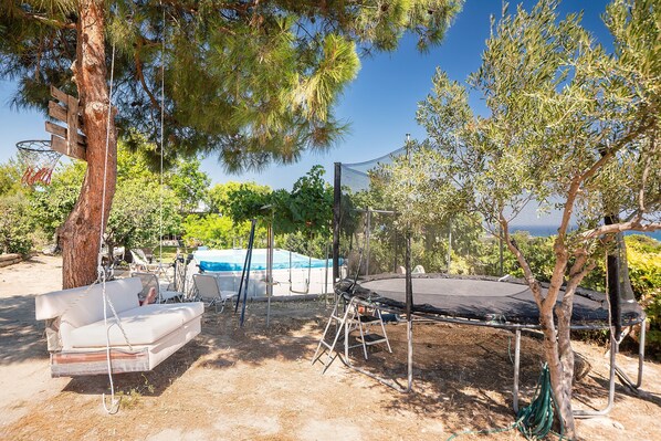 Un jardin avec une balançoire, un trampoline et une piscine.