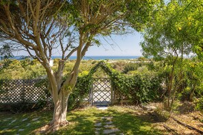 Un jardin offrant une vue sur la mer, une porte en bois et un chemin pavé de pierres.