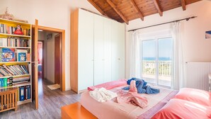 Ein Schlafzimmer mit Bett, Bücherregal, Kleiderschrank und Balkon mit Blick.