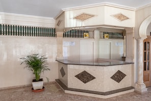 A reception area with a marble counter, a potted plant, and a sign indicating a waiting area.