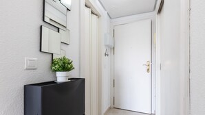 Een gang met een zwarte kast, een potplant, een witte deur en een lichtschakelaar op de muur.