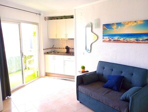 Una sala de estar con un sofá azul y un cuadro de una playa.