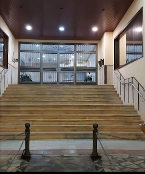A staircase leading to a gated entrance with a view of the outside through large windows.