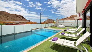 A swimming pool with lounge chairs and a view of a mountainous landscape. - Villa "Tauro 31" with Sea Views, Private Pool, and Wi-Fi (Mogán)