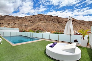 A rooftop pool with artificial grass, a lounge chair, and a mountain backdrop. - Villa "Tauro 31" with Sea Views, Private Pool and Wi-Fi (Mogán)
