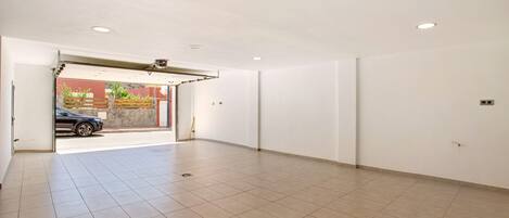 A spacious room with a tiled floor, a door leading outside, and a ceiling with recessed lighting.