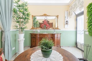 Un comedor con una mesa redonda, una planta en maceta, un espejo y un armario de madera.