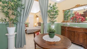 Une pièce comprenant une table à manger, des chaises, une plante en pot, un miroir et un lit.