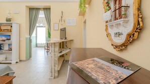 Une pièce avec une table en bois, un tableau encadré, une bibliothèque et une fenêtre avec des rideaux.