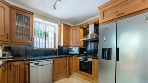 Une cuisine avec des meubles en bois, un réfrigérateur en acier inoxydable, un lave-vaisselle et un four à micro-ondes.