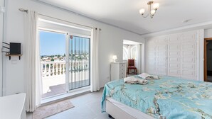 Une chambre à coucher comprenant un lit, un bureau, une chaise, une armoire et un balcon avec vue.