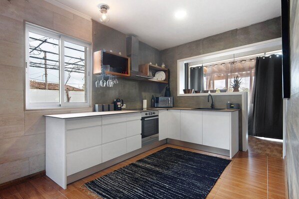 A modern kitchen with a central island, built-in appliances, and a large window with curtains.
