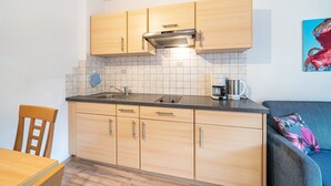 Eine kleine Küche mit Holzausstattung, einer Arbeitsfläche und einer Kaffeemaschine.