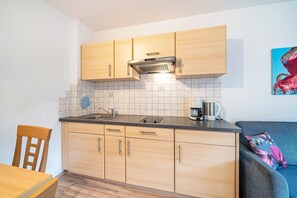 Eine kleine Küche mit Holzausstattung, einer Arbeitsfläche und einer Kaffeemaschine.