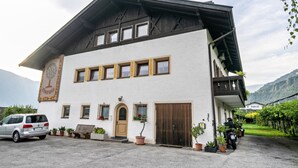 Ein Gebäude mit weißer Fassade, mehreren Fenstern, einer Holztür und einem Balkon.