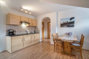 Una cocina moderna con armarios de madera, una cafetera y un comedor con mesa y sillas.