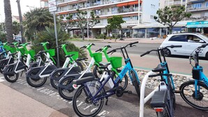 Een rij fietsen geparkeerd op een straat, met een meerlaags gebouw op de achtergrond.
