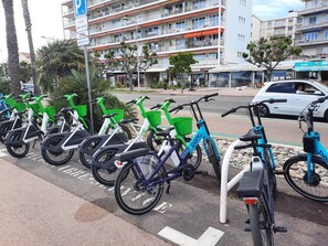 Una fila de bicicletas estacionadas en una calle, con un edificio de varios pisos al fondo.