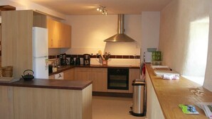 A modern kitchen with wooden cabinets, a stainless steel range hood, and a central island with a kettle.