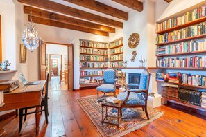 A spacious living room with wooden floors, a fireplace, and a large collection of bookshelves filled with books.