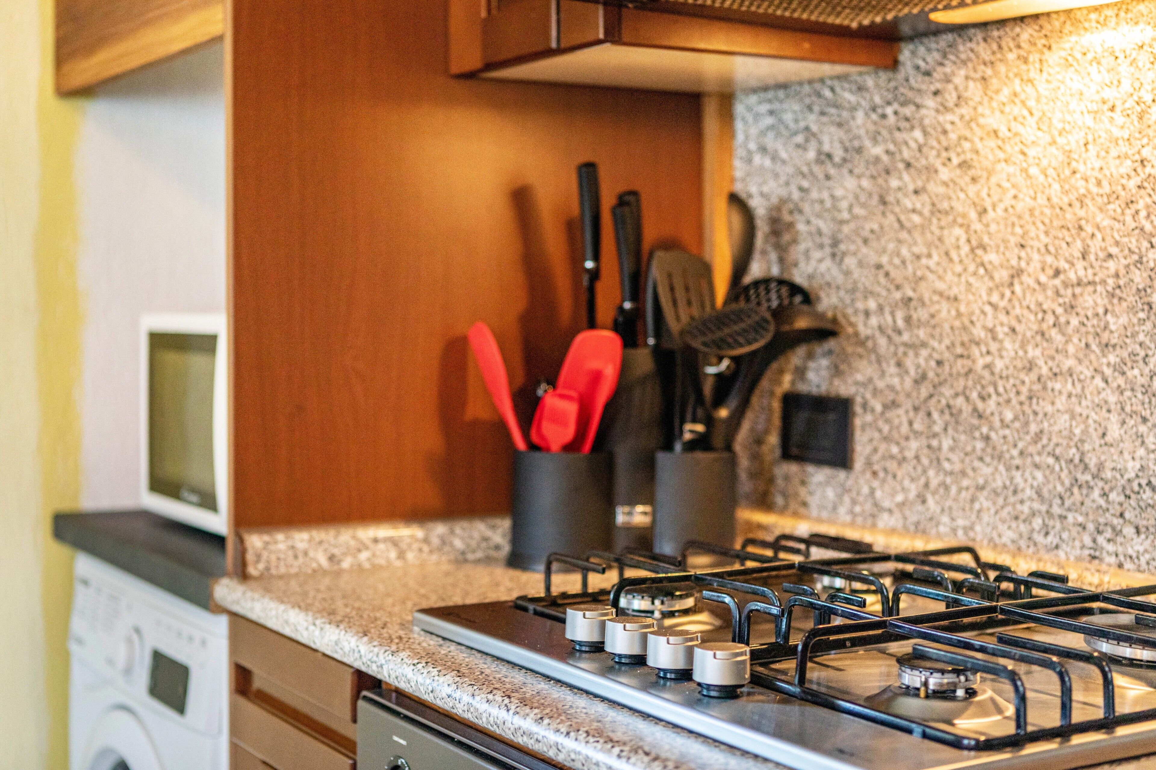 Una cocina con estufa a gas, microondas y lavadora.
