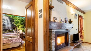 A bedroom with a bed, a fireplace, and a view of a waterfall through a window. - Lo Sondzo Holiday Home – Your Dream Stay in Valle d'Aosta (Nus)