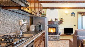 A kitchen with granite countertops, a gas stove, and wooden cabinets. - Lo Sondzo Holiday Home – Your Dream Stay in Valle d'Aosta (Nus)
