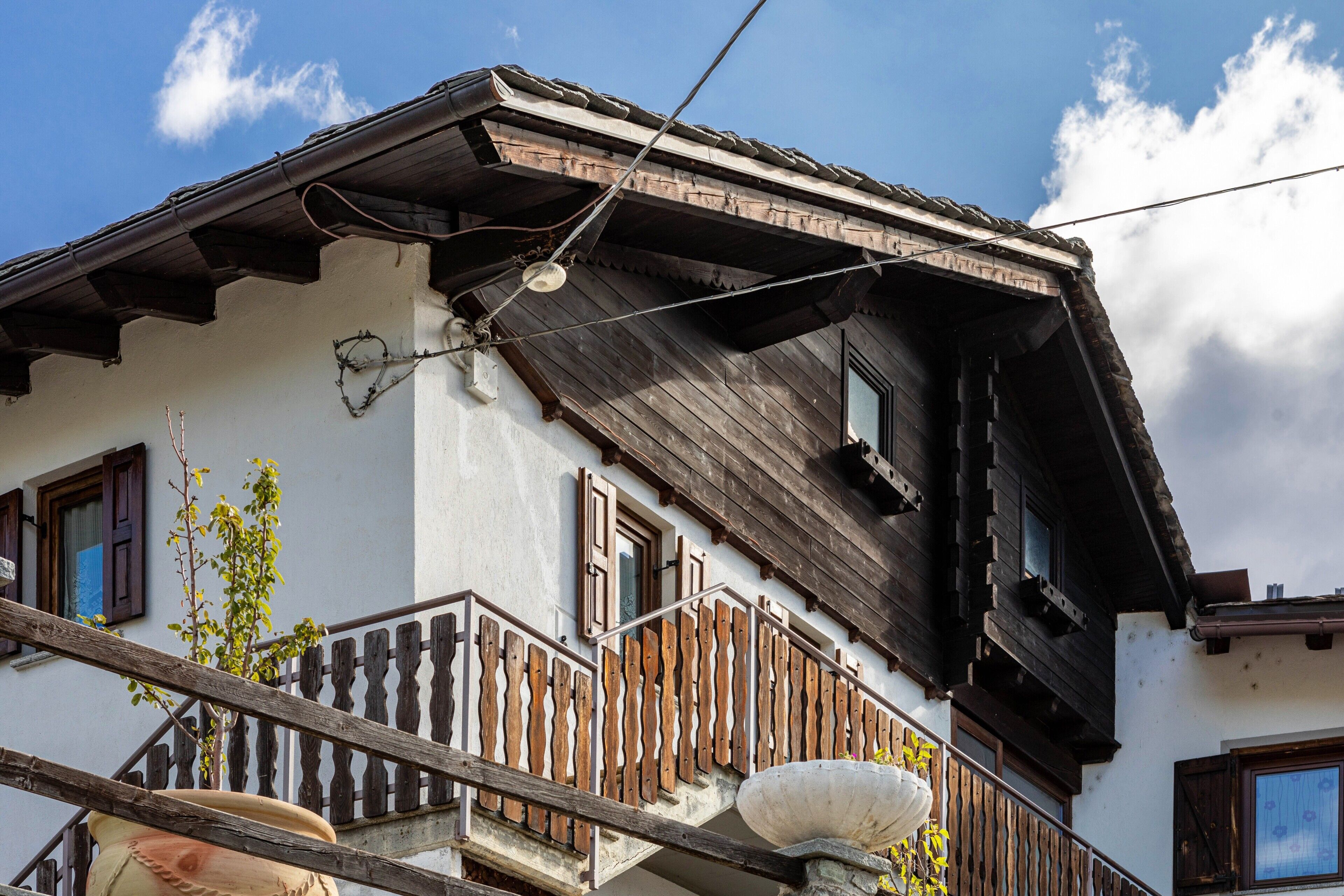 Ein traditionelles Gebäude mit einem Holzbalkon, einem Fenster mit Fensterläden und einer sichtbaren Treppe.