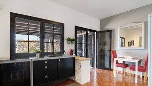 A modern kitchen with a built-in oven, a white dining table with red chairs, and a large mirror above the table. - Vacation Home 'Casa Jess' with Private Terrace, Private Garden and Wi-Fi (Tías)