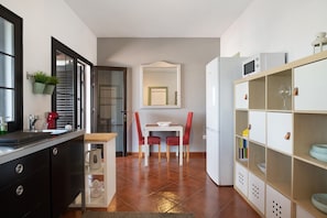 Una cocina moderna con zona de comedor, un refrigerador blanco y una estantería empotrada.