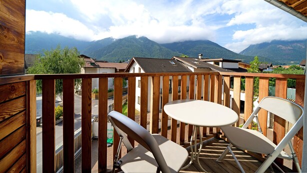 A balcony with a view of mountains, a table, and two chairs. - Holiday Apartment 'Wielander B West' with Mountain View, Shared Garden and Wi-Fi (Laces)