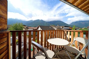 Un balcón con vistas a montañas, una mesa y dos sillas.