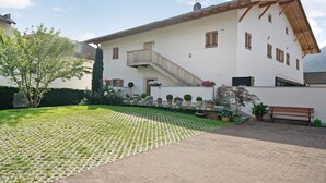 A two-story building with a staircase leading to the upper floor, a paved courtyard, and potted plants. - Holiday Apartment 'Wielander B West' with Mountain View, Shared Garden and Wi-Fi (Laces)
