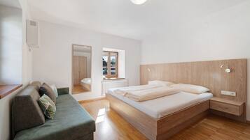 Une chambre à coucher comprenant un lit, un canapé, une tête de lit en bois, une table de chevet et une fenêtre.