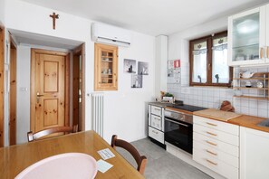 Une cuisine moderne avec une table à manger en bois, un four encastré et un dosseret de carrelage blanc.