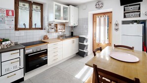 Une cuisine moderne avec des meubles blancs, un four encastré, un évier et une table à manger avec des chaises.