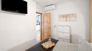 Une chambre d’hôtel équipée d’un téléviseur à écran plat, d’un radiateur, d’une porte en bois, d’une armoire et d’un tableau représentant des arbres.