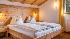 A wooden bed with a headboard, two bedside tables, and a window with curtains.