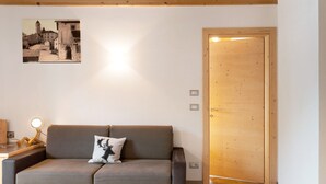 A modern living room with a grey sofa, a wooden door, and a wall-mounted picture.