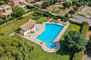 Una propiedad residencial con piscina, un patio con mobiliario exterior y un pequeño jardín.