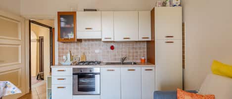 Een koelkast, een oven, een kookplaat, kookgerei, borden en bestek