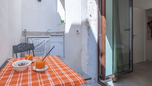 Une petite cuisine avec un évier, une table recouverte d’une nappe à carreaux et une chaise.