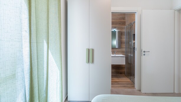 Une chambre à coucher comprenant un lit, une armoire, une salle de bain avec un miroir et une douche.