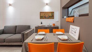 Un coin repas avec une table dressée pour quatre personnes, un canapé gris et un tableau accroché au mur.