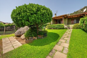 Une maison avec un chemin en pierre, un grand arbre et une pelouse bien entretenue.