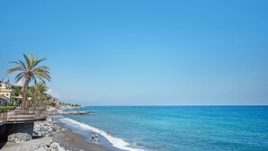 A beach with a rocky shoreline, palm trees, and buildings in the background. - Apartment 'Casa Cogoleto Terrace and Parking' with Sea View, Wi-Fi and Air Conditioning (Cogoleto)