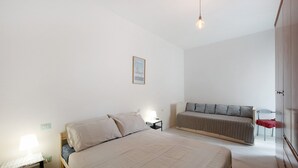 A bedroom with a bed, bedside table, lamp, and a sofa. - Apartment 'Casa Cogoleto Terrace and Parking' with Sea View, Wi-Fi and Air Conditioning (Cogoleto)