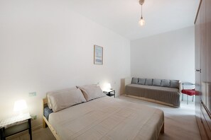 Una camera da letto con un letto, un comodino, una lampada e un divano.