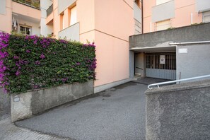 Un vicolo cittadino stretto, con un muro in cemento da un lato e l'ingresso di un edificio dall'altro.