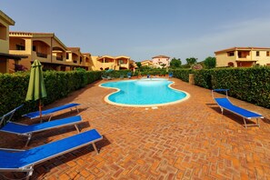 A swimming pool with lounge chairs and a brick pathway. - Apartment 'Casa Vacanze Albicocca' with Shared Pool, Private Terrace & Air Conditioning (olbia)